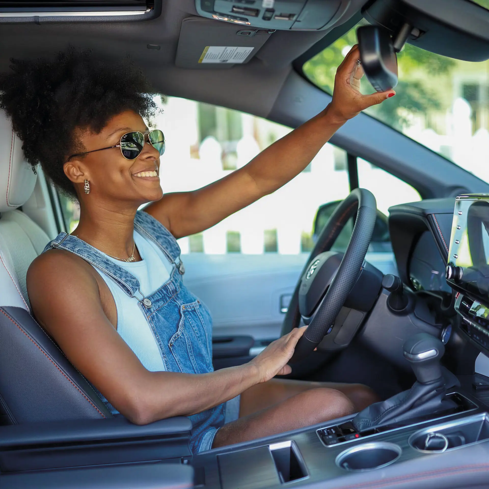 Condutora sorridente ao volante de um automóvel contemporâneo